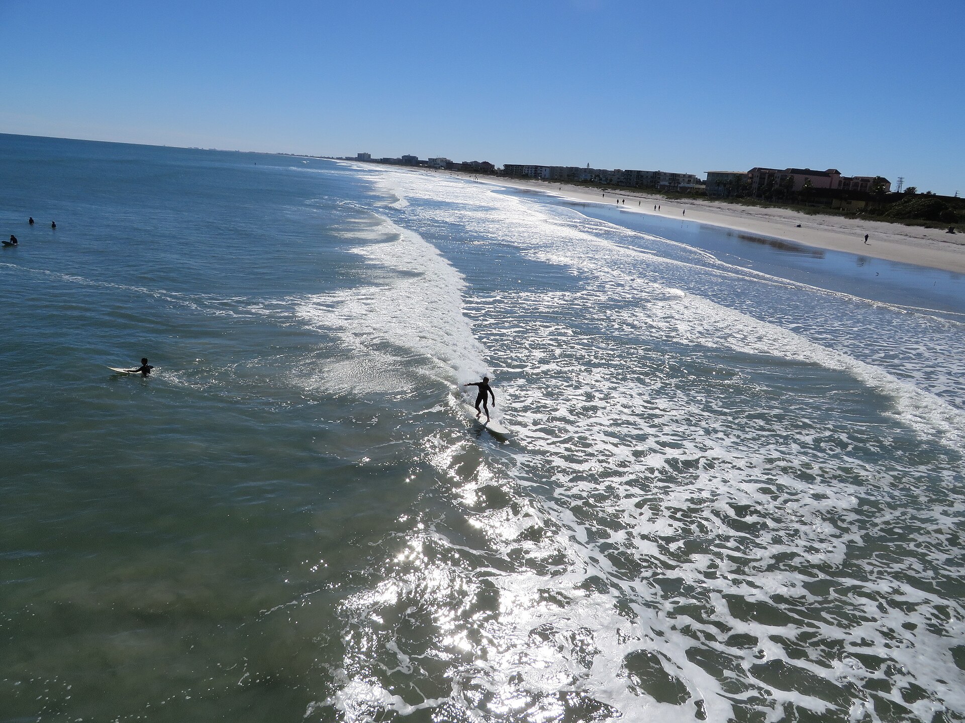 A surfer riding a wave at the Cocoa Beach Pier, the surf scene that became the town's most durable pop-culture export.