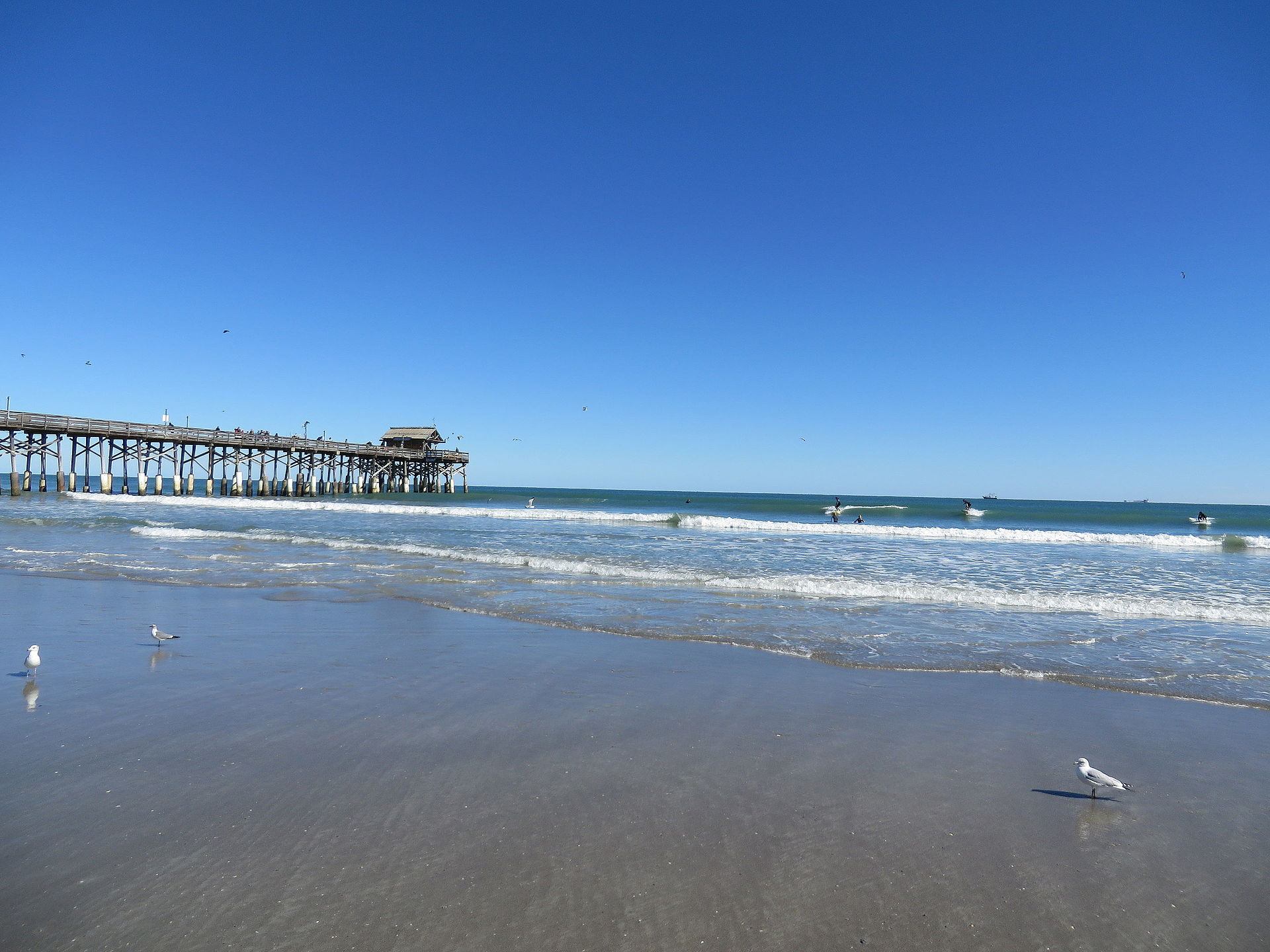 Surfers in the water beside the Cocoa Beach Pier.