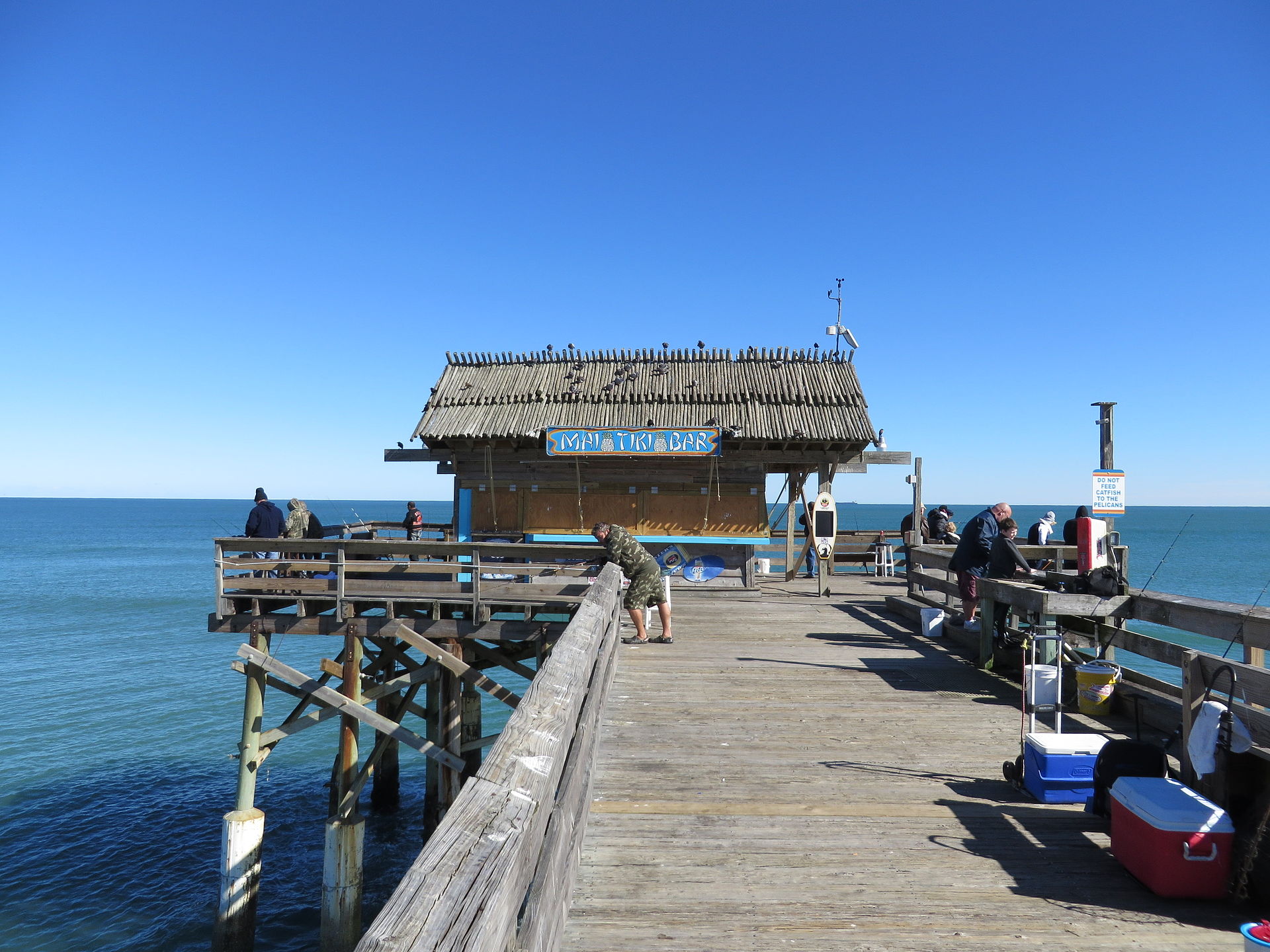 Aerial view of the Cocoa Beach Pier extending into the Atlantic, with the wide barrier-island beach beneath it.